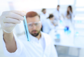 image is blurred. young scientist holding tube with the reagents