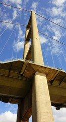Obraz premium One end of the Humber Bridge looking up from underneath with blue sky and white clouds behind