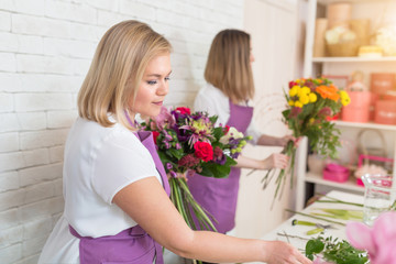 Professional florist decorator in flower shop compose new bouquet. Woman work with tulip assortment, artist workplace