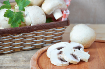 Fresh white mushrooms champignon in brown basket on wooden background. Top view. Copy space