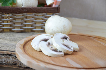 Fresh white mushrooms champignon in brown basket on wooden background. Top view. Copy space