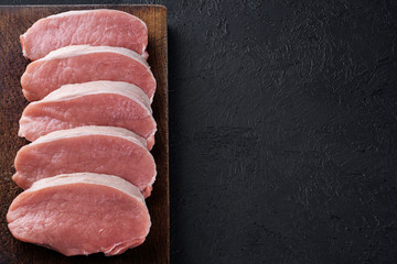 Raw sliced pork loin on a dark background. Fresh meat.