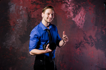 Studio portrait of stylish professional photographer man with camera, wear on blue shirt and necktie.