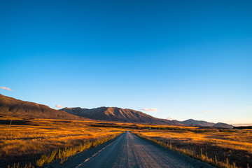 Beautiful scene of the road among the yellow grassland and the mountain beside lake Tekapo.