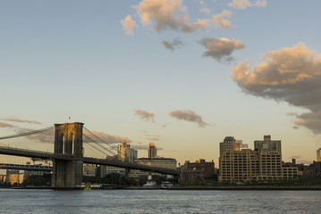 Fototapeta premium Brooklyn bridge at sunset/Hudson river with the Brooklyn bridge and Brooklyn buildings on a late summer sunset.
