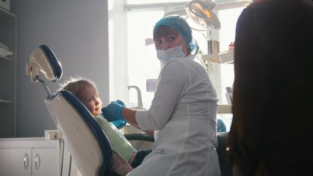 Little girl with mommy in dentist chair - child is playing