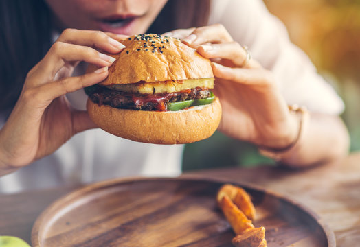 Woman Eating Meat Burger In Restaurant.