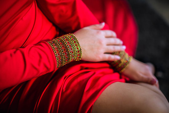 Women's gentle hands, a jewelry bracelet with ruby stones on his hand. Girl in red long dress