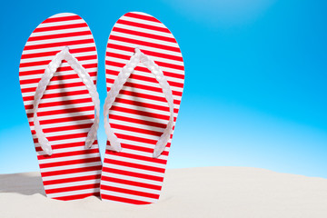 Striped flip flops on the sandy beach. Sky with copy space