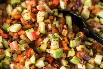 Sliced vegetables are stewed in a frying pan close up - zucchini, pepper, onions, tomatoes