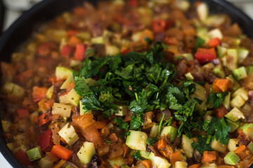 Sliced vegetables are stewed in a frying pan close up - zucchini, pepper, onions, tomatoes