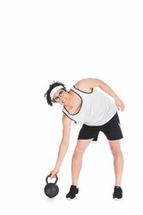 Thin sportsman in eyeglasses raising kettlebell isolated on white