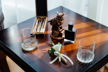 Wedding boutonniere, cigars and alcohol on a wooden table.