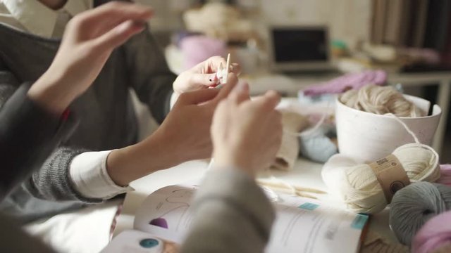 Mother learning daughter knitting needles yarn in home. Woman hands knitting woolen thread in workshop
