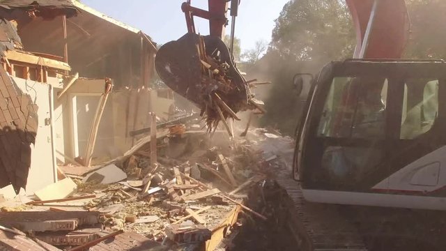 Close On Excavator Bucket Lifting Debris From Demolished House