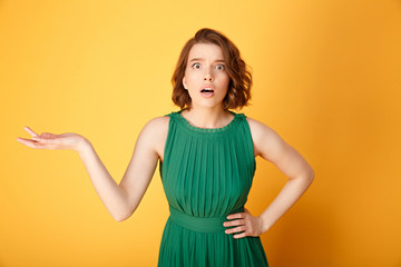 portrait of shocked woman with outstretched arm looking at camera isolated on orange