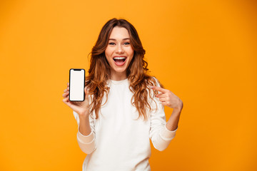 Happy brunette woman in sweater showing blank smartphone screen