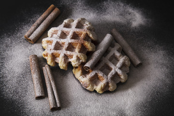 fresh belgian wafles on dark background with cinnamon sticks