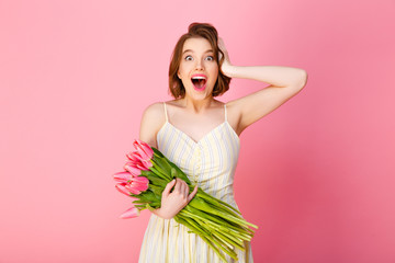 portrait of excited woman with bouquet of pink tulips isolated on pink