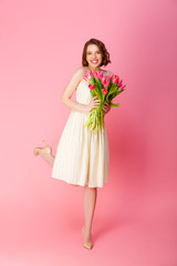 attractive smiling woman with bouquet of spring tulips isolated on pink