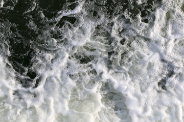 stormy creek. wave and foam in the flow. splashes, bubbles, waves, stream, ripples and crests of waves in a fast forest stream in winter