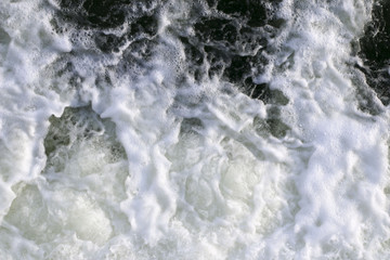 stormy creek. wave and foam in the flow. splashes, bubbles, waves, stream, ripples and crests of waves in a fast forest stream in winter