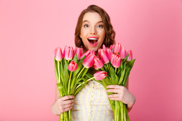 portrait of happy woman with bouquets of tulips isolated on pink