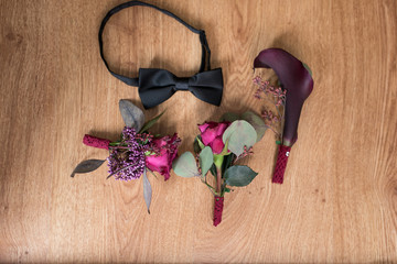 Three Decoration buttonhole and a black necktie on brown background. Decoration made of roses, decorative plants. 