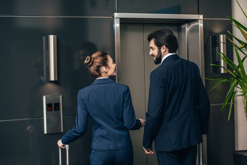 Rear view of business people with luggage waiting for elevator together © LIGHTFIELD STUDIOS