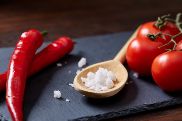 Vegetarian still life with fresh grape tomatoes, pepper and salt in wooden spoon on wooden background, selective focus