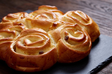Homemade rose bread on black cutting board on vintage background, close-up, shallow depth of field