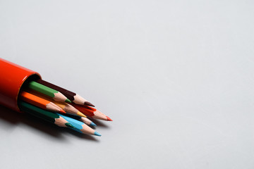 Colored pencils in a red case on white background.