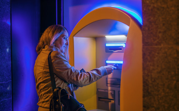 Mature woman taking money from an ATM.