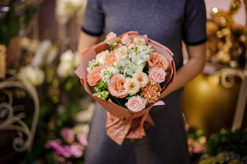 Woman holding a bouquet of beige roses and other flowers