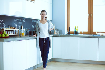 Young woman with orange juice and tablet in kitchen.