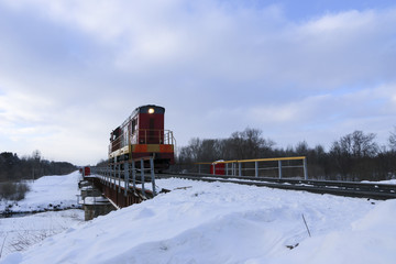 Shunting locomotive to ride on the railway bridge in winter. The locomotive is moving along the...
