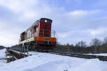 Shunting locomotive to ride on the railway bridge in winter. The locomotive is moving along the...