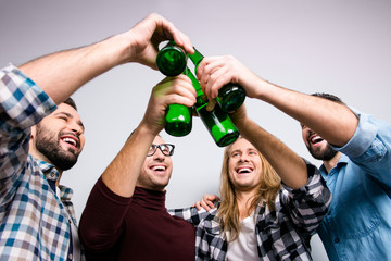 Ethnicity diversity victory triumph union community concept. Low-angle photo of four friendly excited cheerful toothy laughing guys clinking bottles, checkered jeans shirt, fan soccer world cup