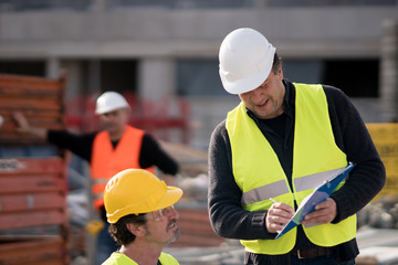 Civil engineer giving instructions to construction workers on construction site