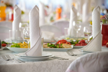 Beautiful table setting with crockery and flowers for a party, wedding reception or other festive event. Glassware and cutlery for catered event dinner