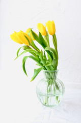 Bouquet of yellow in a vase on a white background, concept of Women's Day or Mother's Day or Easter in March or April. Spring mood, copy space.