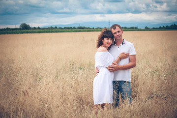 Happy couple on wheat field with a bouquet of camomiles