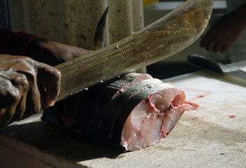 Découpe du poisson sur le marché de Tartane, gros plan sur la machette et la main, Martinique, Caraïbes