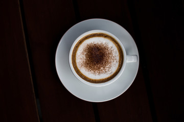 Coffee in a white cup on a wooden table.