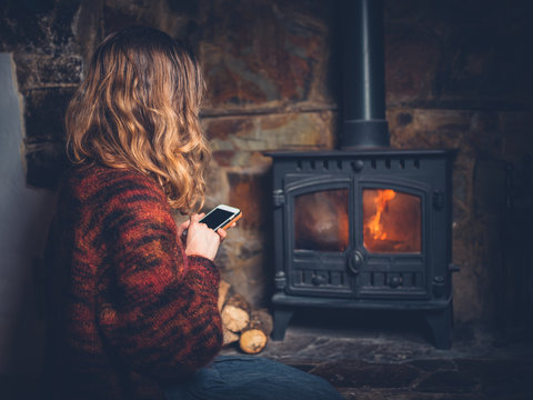 Woman using smart phone by the fireplace