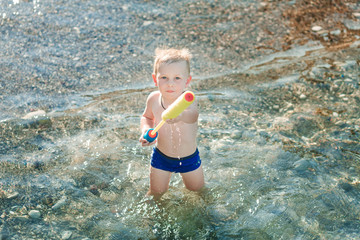 Cute happy kid playing with water pistol