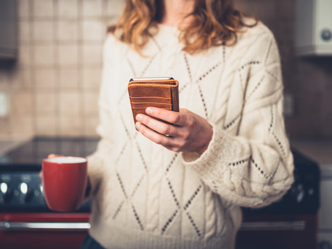 Woman drinking tea and using phone in kitchen