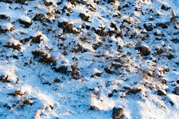 Snow on the ground in the rays of the sunset as a background