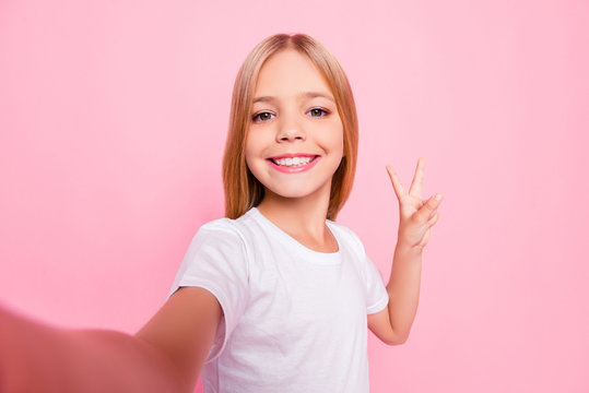 Close up portrait of cute lovely sweet funky adorable beautiful charming with toothy with blonde hairstyle beaming smile girl making v-sign gesture white tshirt isolated on pink background