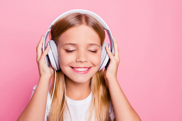 Fototapeta premium Modern technology concept. Close up portrait of cute tender sweet lovely with beaming toothy smile closed eyes girl enjoying nice tune on headphones isolated on bright pink background